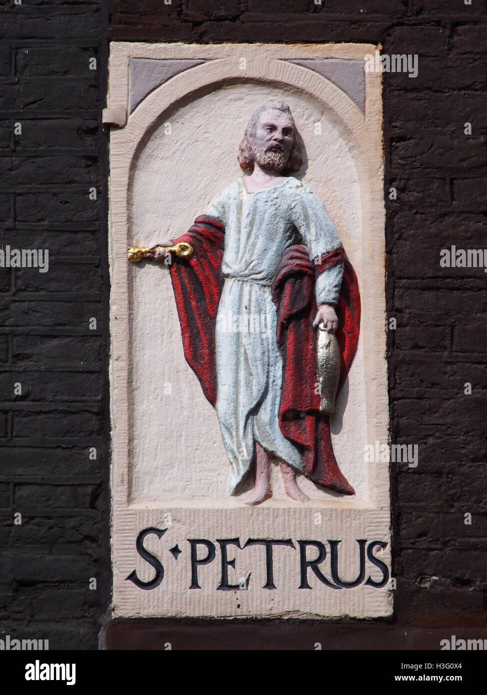 Ein historischer Giebelstein aus Zandhoek mit einem Gravur des Heiligen Peter. Solche architektonischen Elemente waren in niederländischen Gebäuden üblich, die oft religiöse oder symbolische Figuren darstellten. Stockfoto