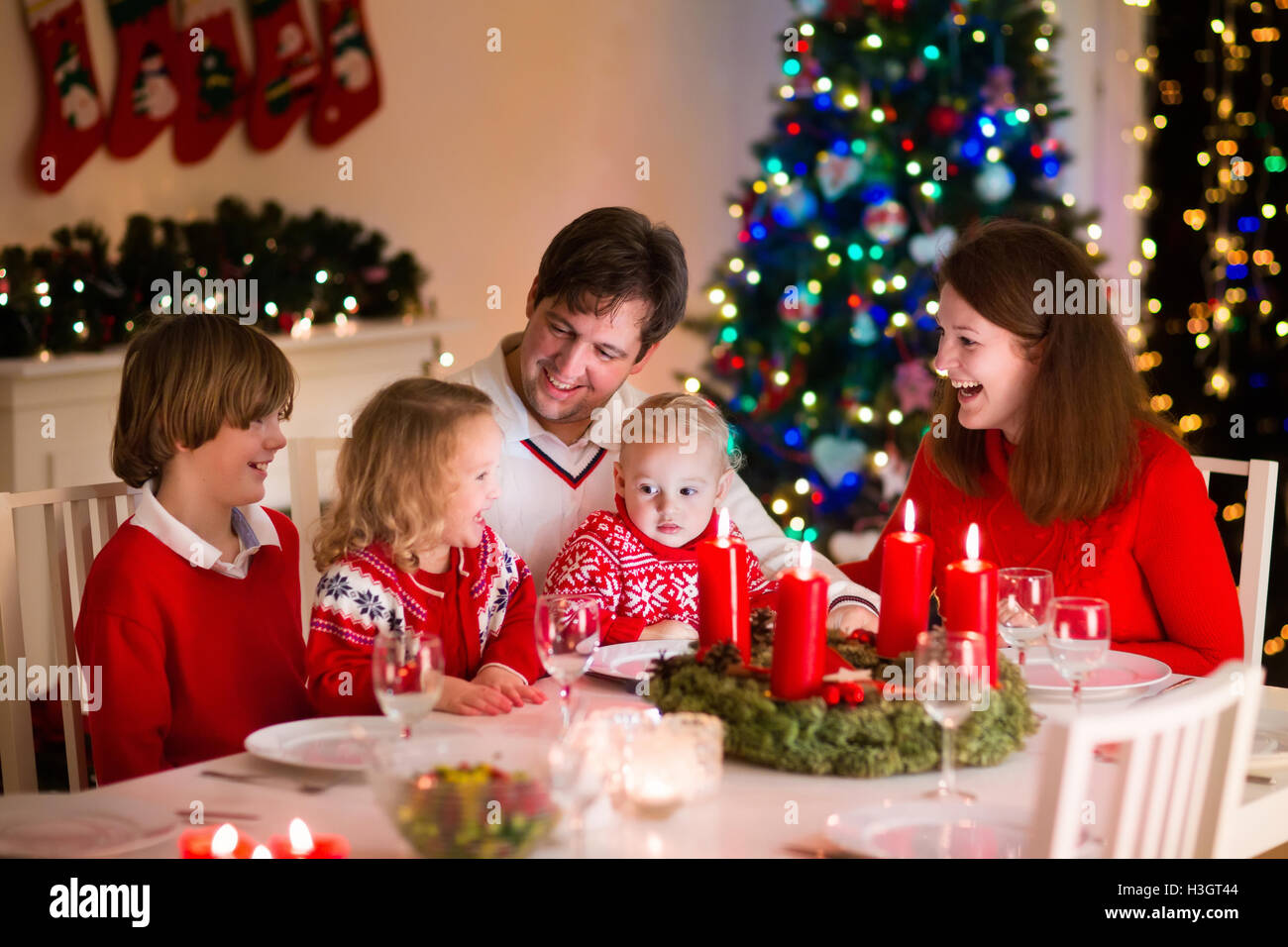 Große Familie mit drei Kindern zu Hause Weihnachten zu feiern. Festliches Abendessen am Kamin 
