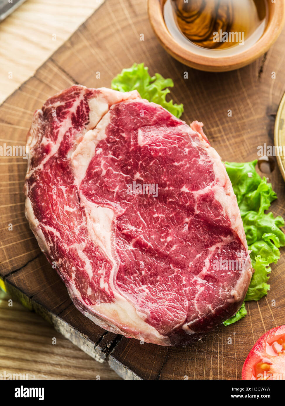 Ribeye Steak mit Gewürzen auf den alten Holztablett. Stockfoto