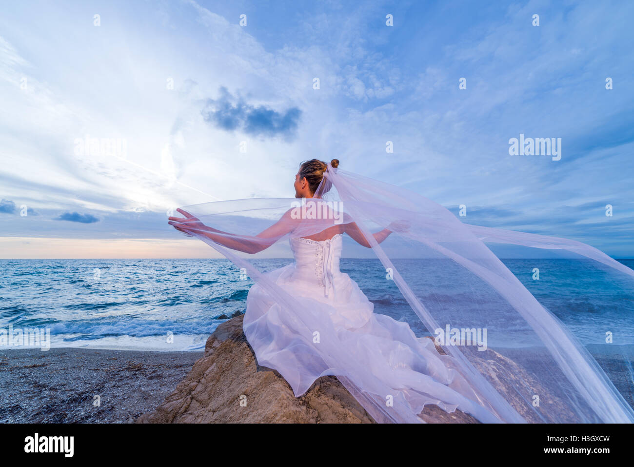 Braut an einem tropischen Strand mit Sonnenuntergang im Hintergrund Stockfoto