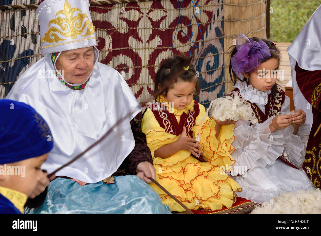 Großmütter und Kinder schlagen Wolle zu Garn neben Jurte Hunnen Village Kasachstan Stockfoto