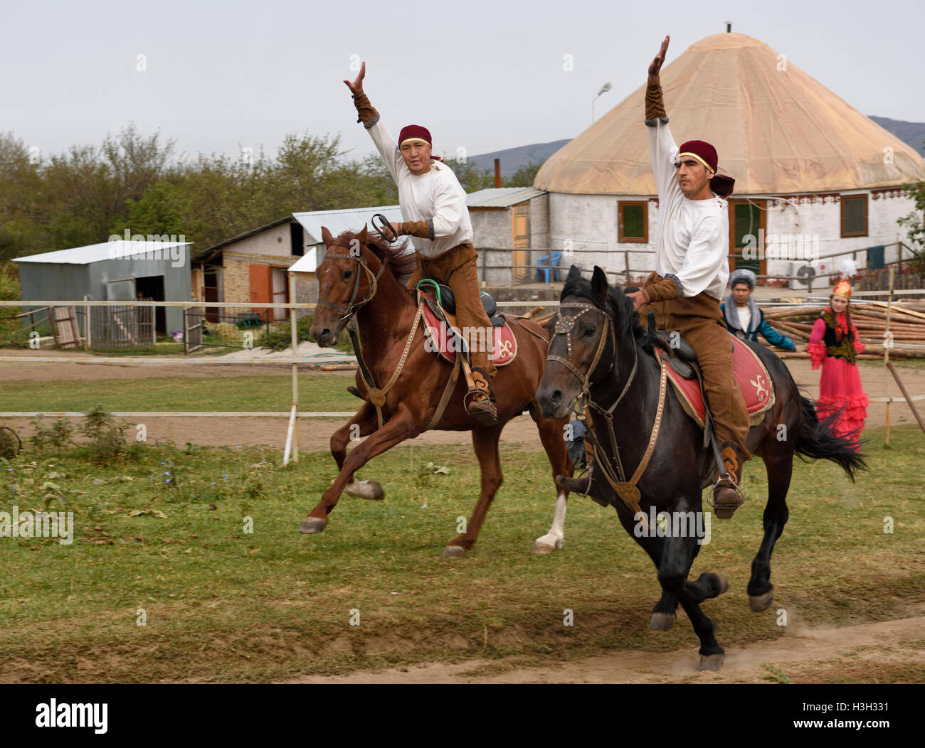 Kasachische Reitern im Galopp vorbei mit Hunnen Dorf Kasachstan erhobenen Armen Stockfoto