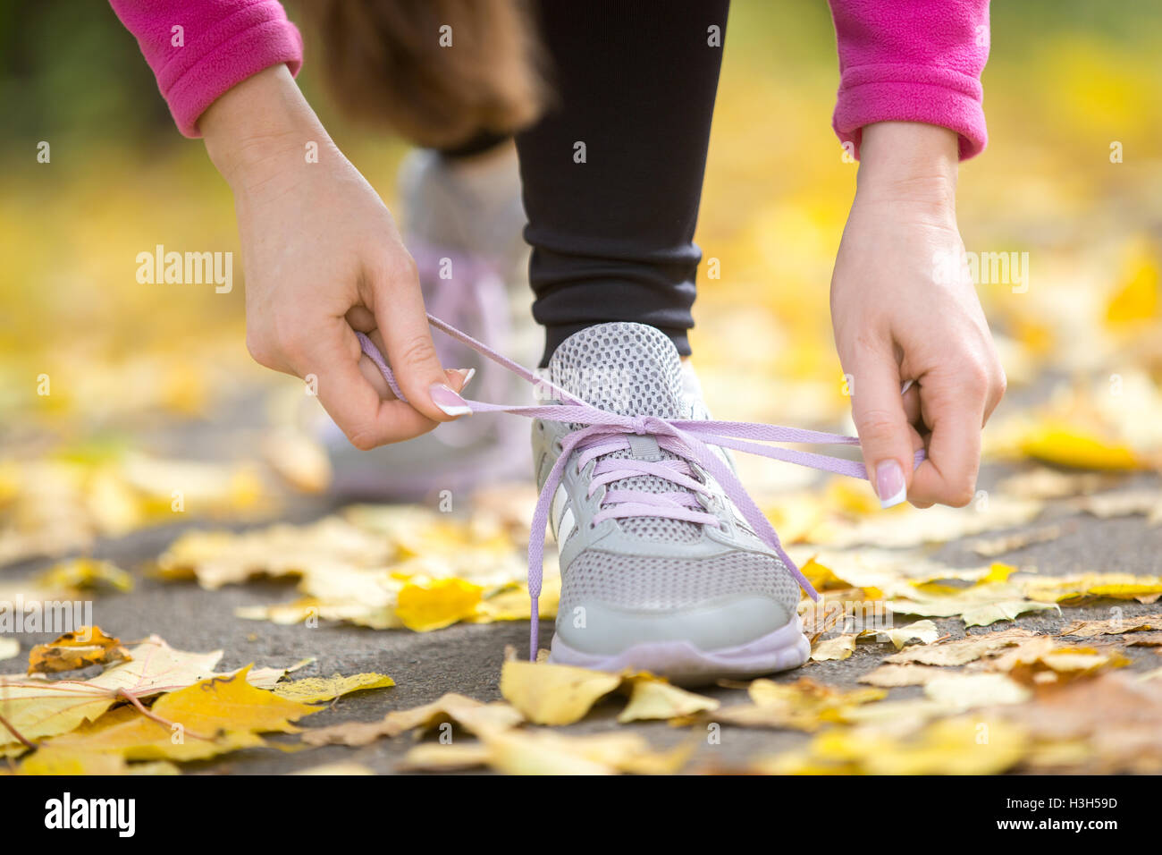 Hände, die Trainer Schnürsenkel binden, auf den Herbst Pflaster Stockfoto