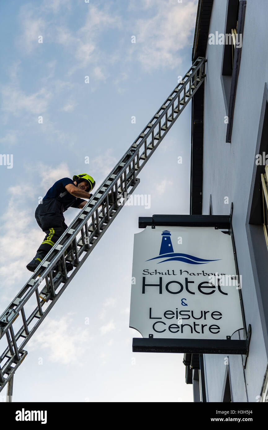 Ein Feuerwehrmann steigt eine Leiter während einer Wohltätigkeitsveranstaltung in Schull, West Cork, Irland. Stockfoto