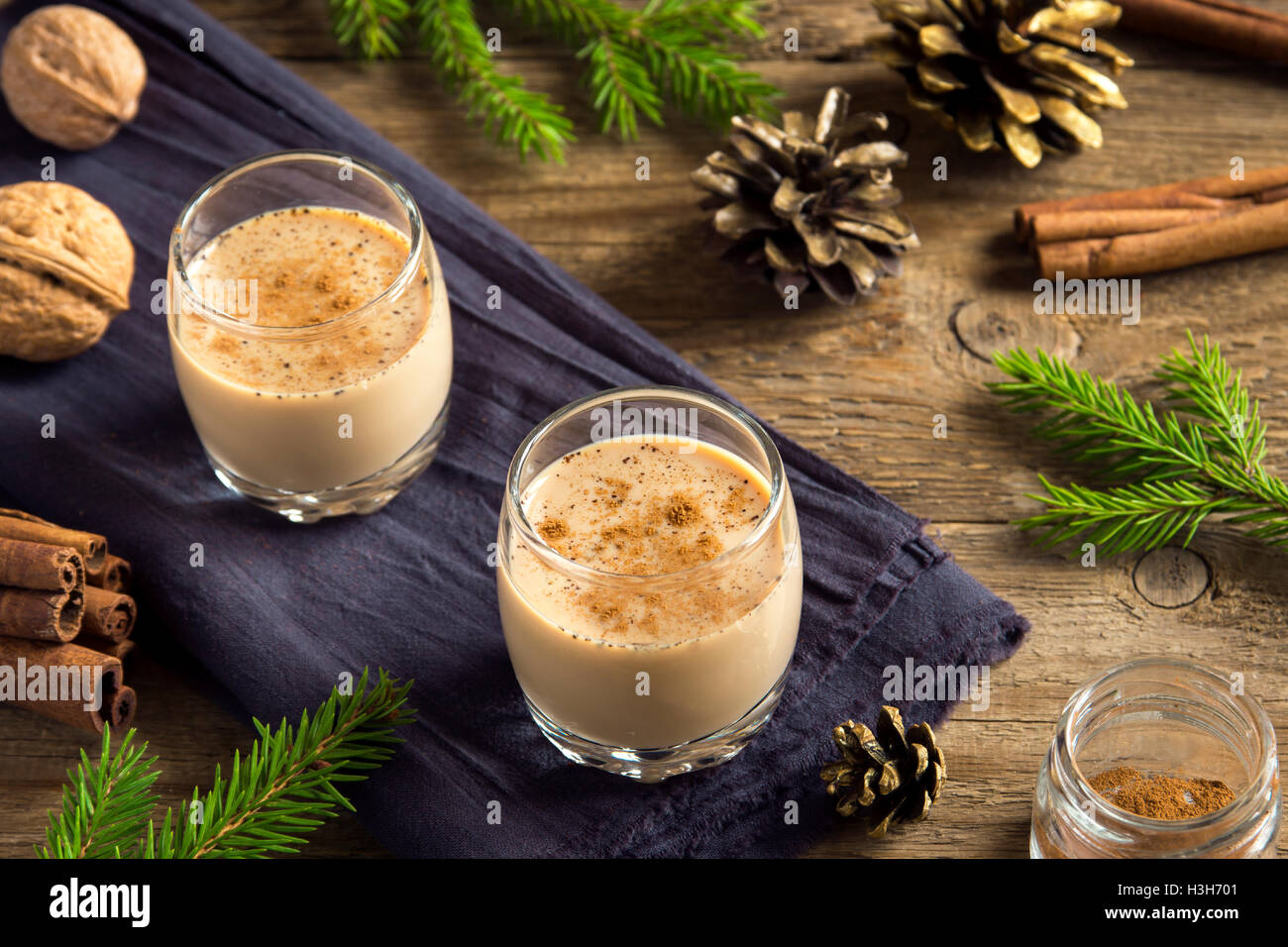 Eierlikör mit Zimt in Gläsern über rustikalen hölzernen Hintergrund mit Weihnachts-Dekor - hausgemachte festliche Weihnachts-drink Stockfoto