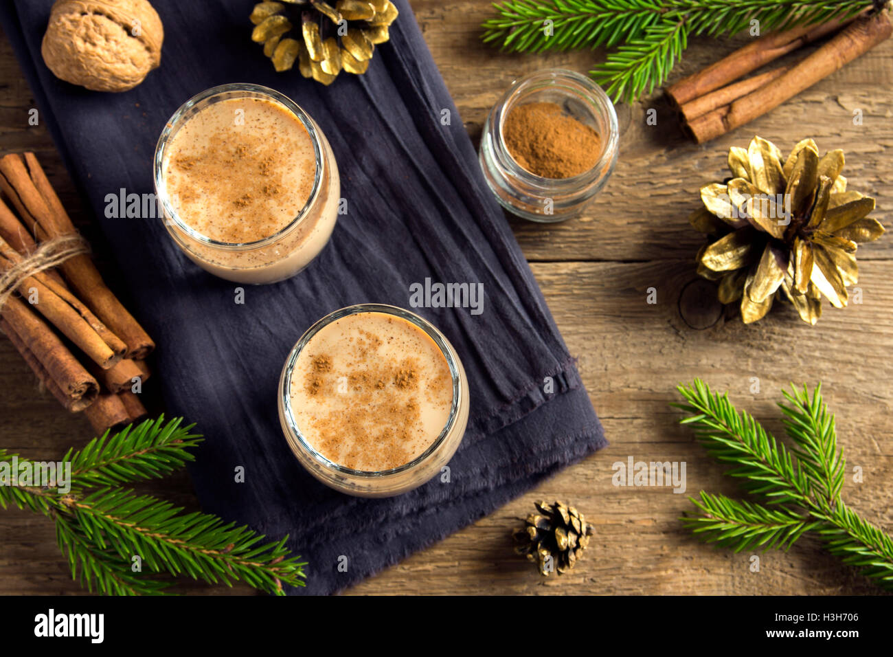 Eierlikör mit Zimt in Gläsern über rustikalen hölzernen Hintergrund mit Weihnachts-Dekor - hausgemachte traditionelle festliche Getränk für Chr Stockfoto