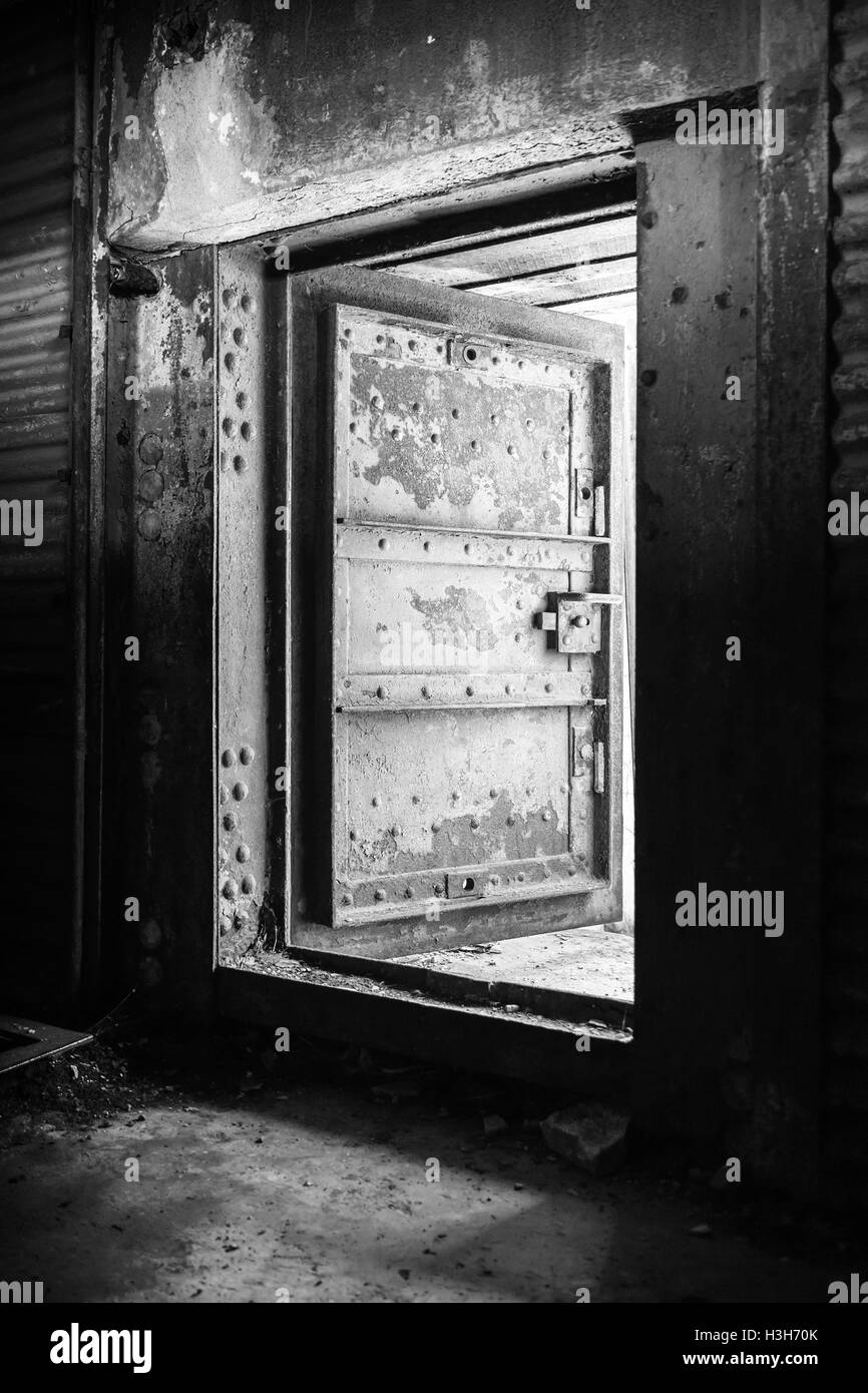 Dunkle grungy industrielle Interieur mit verrosteten Wand zu abstrahieren und schwere Stahltür, schwarz / weiß Foto öffnen Stockfoto