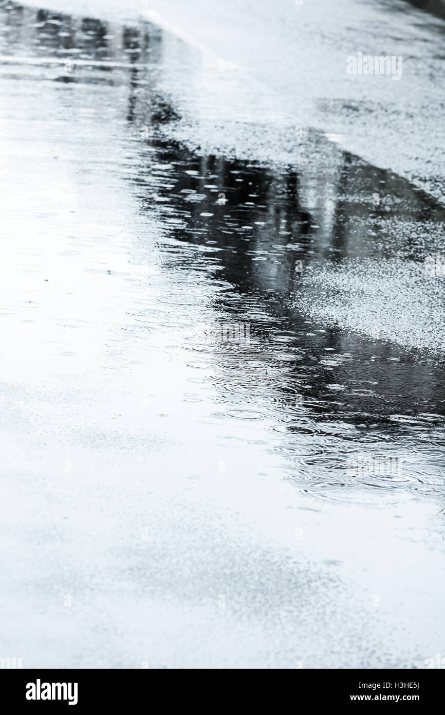 nassen Straßenpflaster mit Regentropfen und Pfützen bei Regen Stockfoto