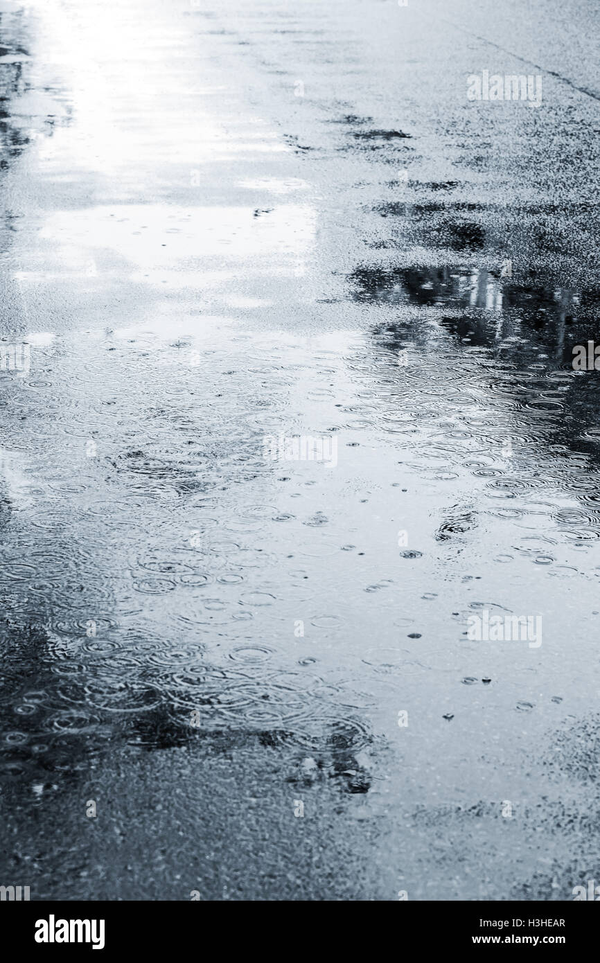 Regentropfen auf nassem Asphalt. nassen Straßenpflaster bei Regen im Herbst. Stockfoto