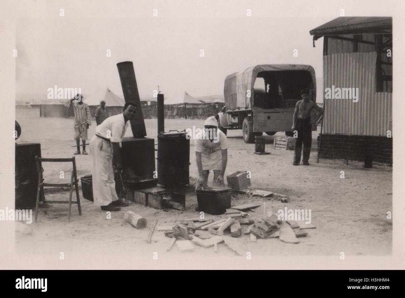 Nicht identifizierte ägyptische Männer, die in einem britischen Armeelager auf einem Holzofen Lebensmittel zubereiten. Foto aufgenommen im Lager des Royal Army Ordnance Corps (RAOC) des 10 Base Ordnance Depot im Gebiet Geneifa Ismailia nahe dem Suez-Kanal 1952 Stockfoto