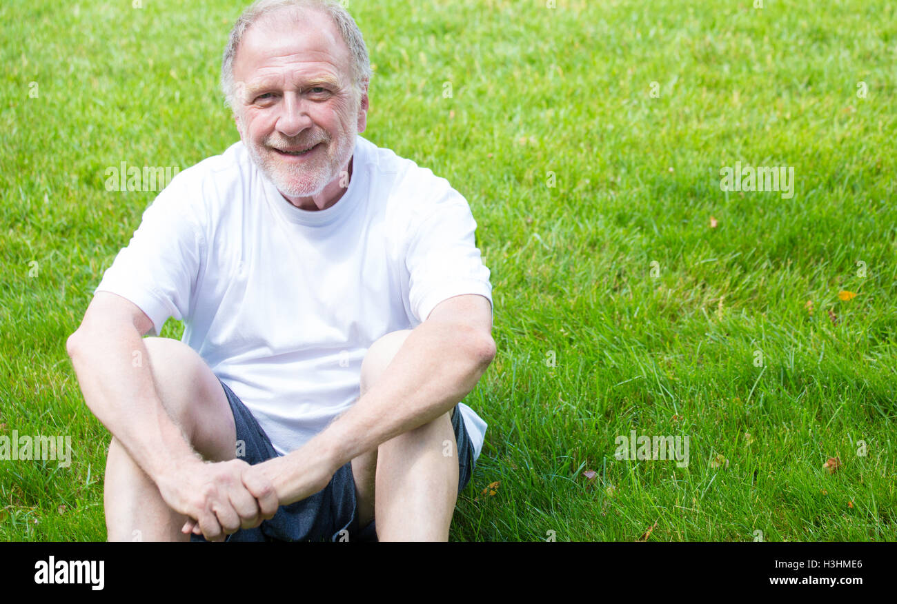 Closeup Portrait von glücklich, selbstbewusst, fröhlich, lächelnden senior reifer Mann in weißem Hemd und Shorts, sitzen Stockfoto