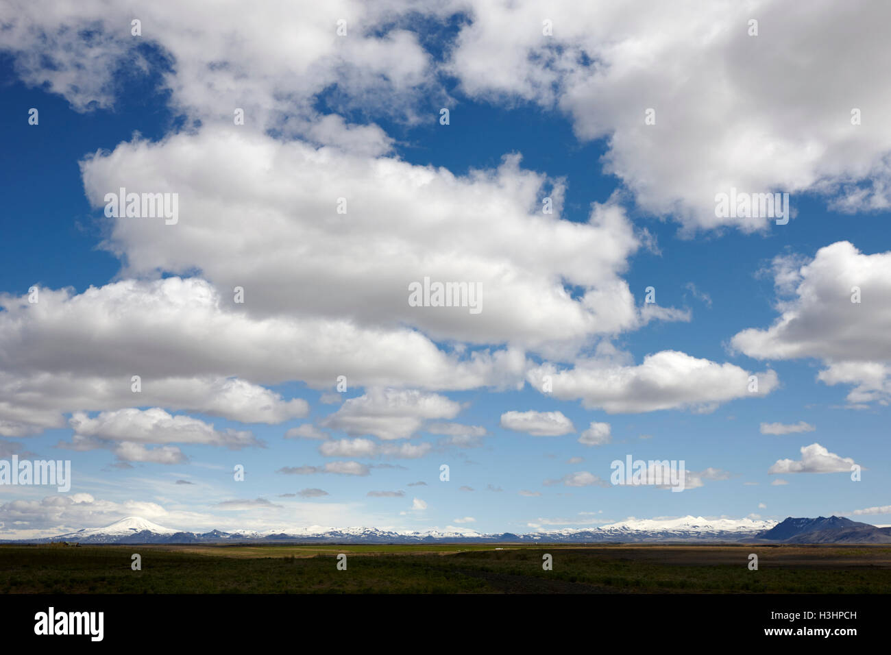 weiße Wolken am blauen Himmel über offene Nutzflächen im Süden Islands Stockfoto