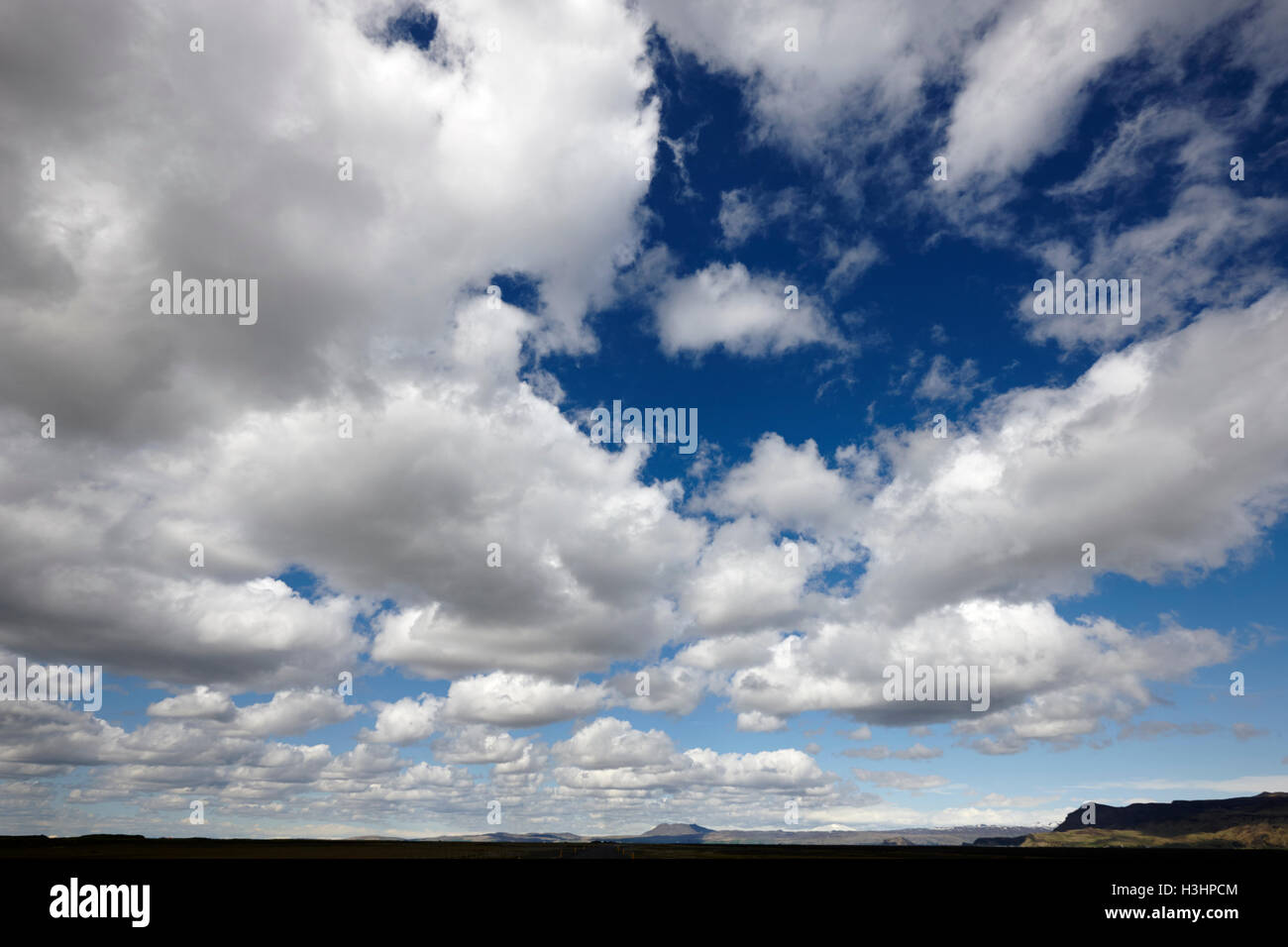weiße Wolken am blauen Himmel über offene Nutzflächen im Süden Islands Stockfoto