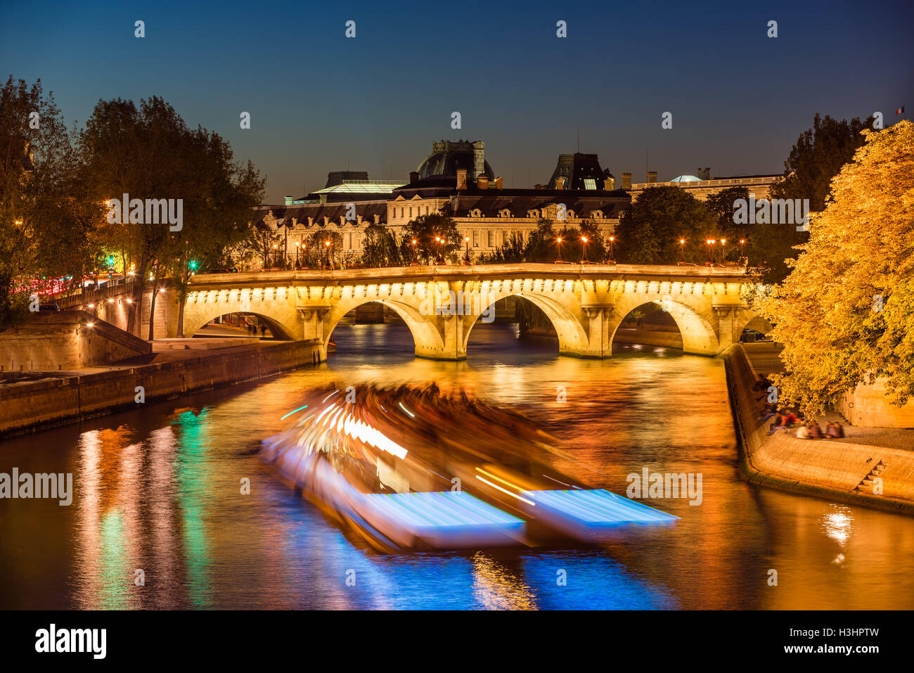 Pont Neuf Brücke beleuchtet und Seineufer in der Dämmerung mit Citylights und Touristenboot. Ile De La Cite, Paris, Frankreich Stockfoto