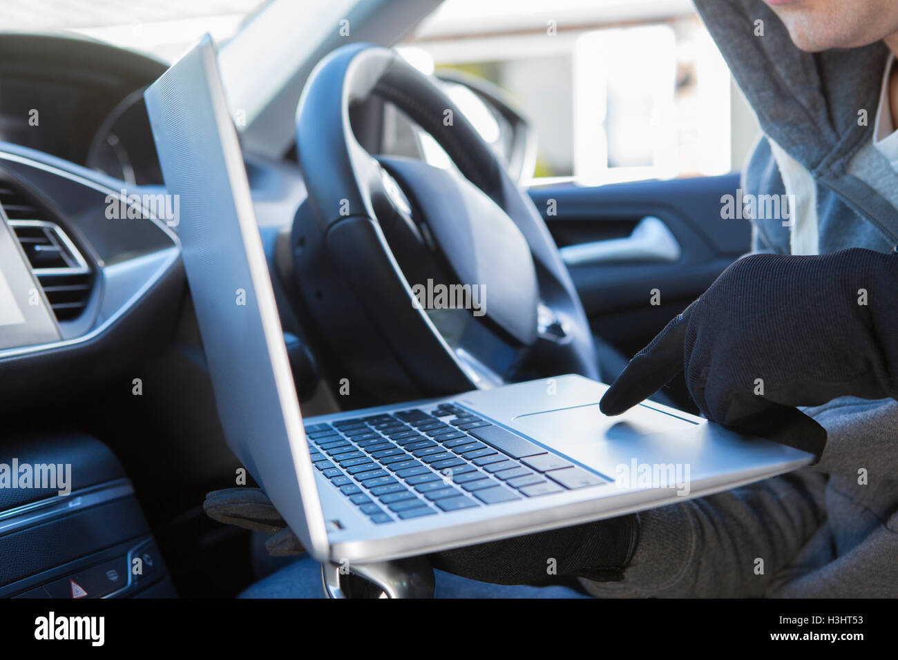 Dieb mit Laptop, Hack in Auto-Sicherheits-Software Stockfoto