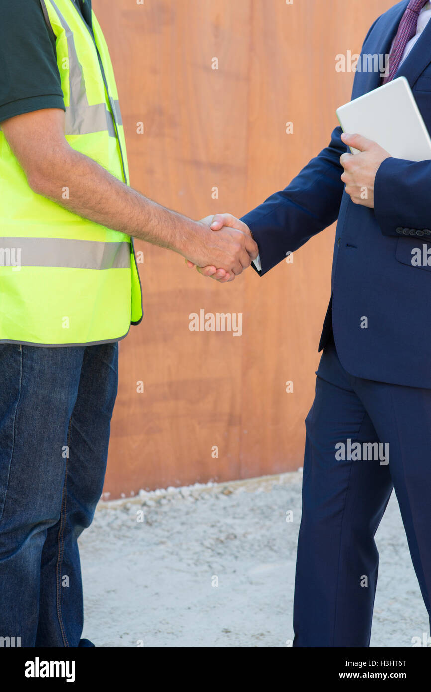 Geschäftsmann Händeschütteln mit Builder auf Baustelle Stockfoto