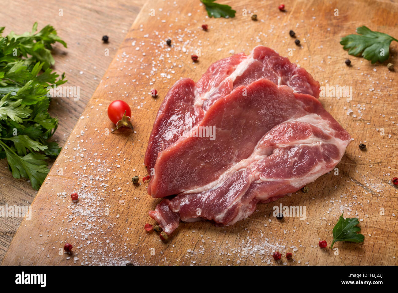 Rohes Schweinefleisch Steaks auf Holzbrett mit Kräutern Stockfoto