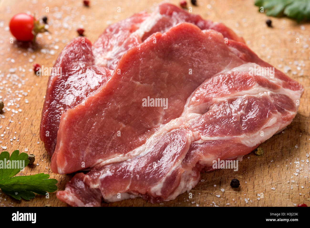 Rohes Schweinefleisch Steaks auf Holzbrett mit Kräutern Stockfoto