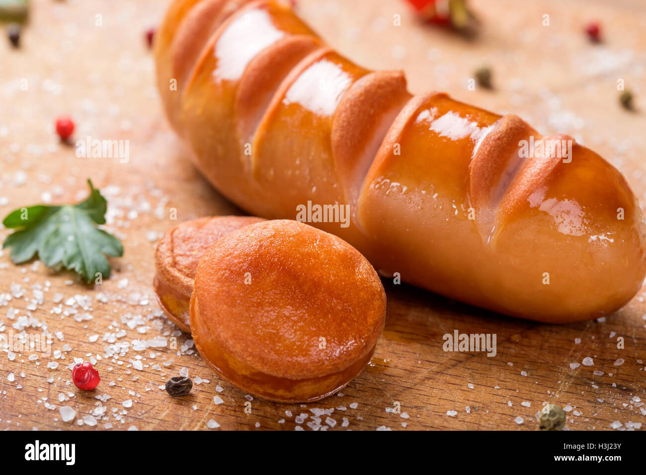 Zwei Scheiben polnische Wurst auf einem Holzbrett mit Kräutern Stockfoto