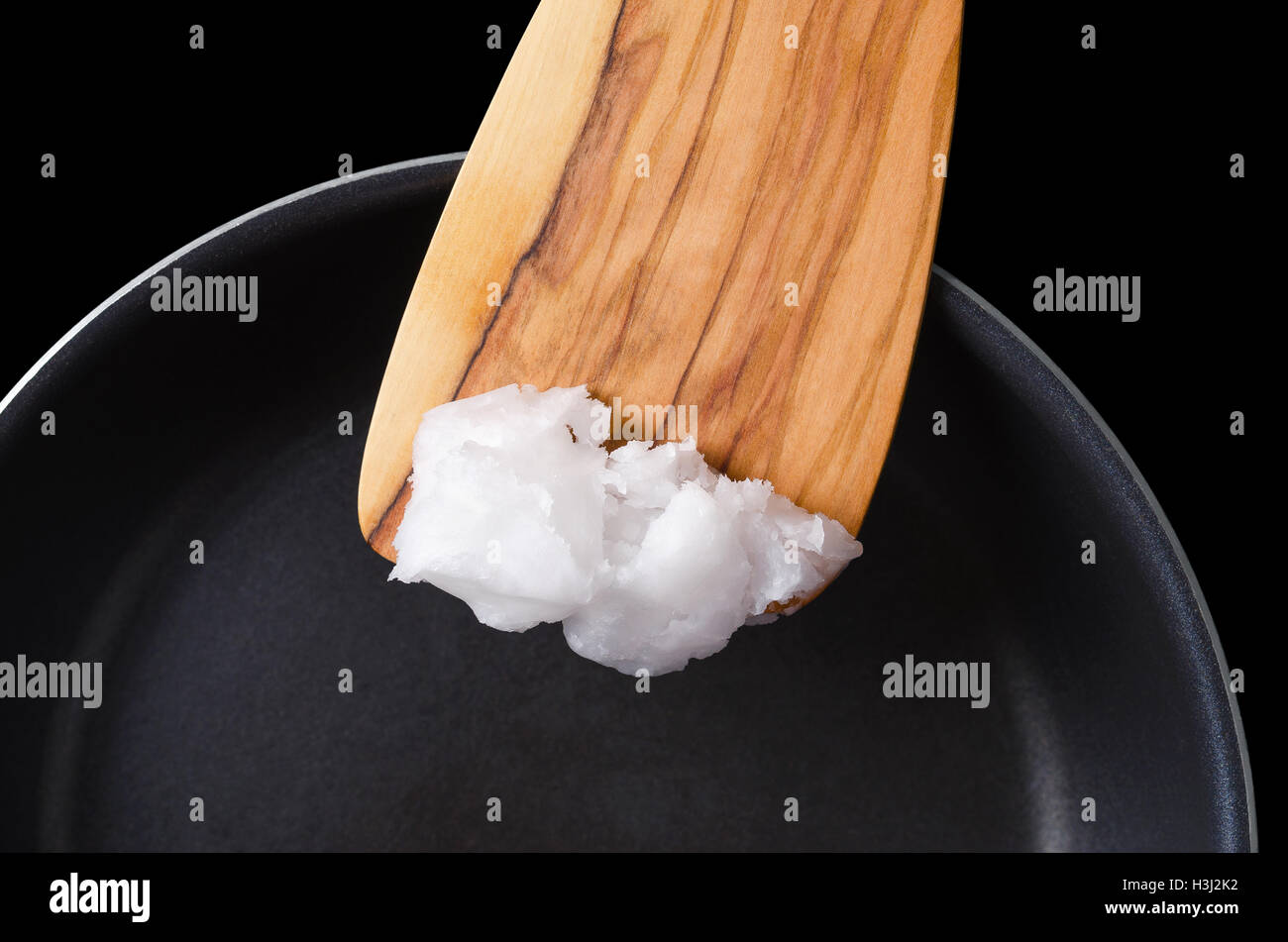 Kokosöl bei Holzspatel über beschichtete Pfanne. Auch Kopra Öl, ein Speiseöl aus dem Kernel von Fleisch der Kokosnuss gewonnen. Stockfoto
