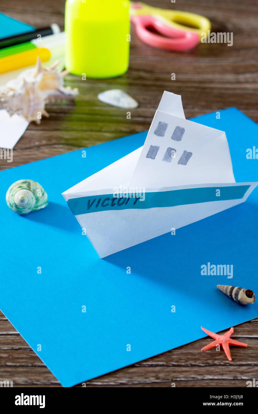 Papierschiff basteln, Origami. Kleber, Schere, Papier, Seesterne und  Muscheln auf einem Holztisch. Kinder Kunst-Projekt, ein Handwerk für  Stockfotografie - Alamy