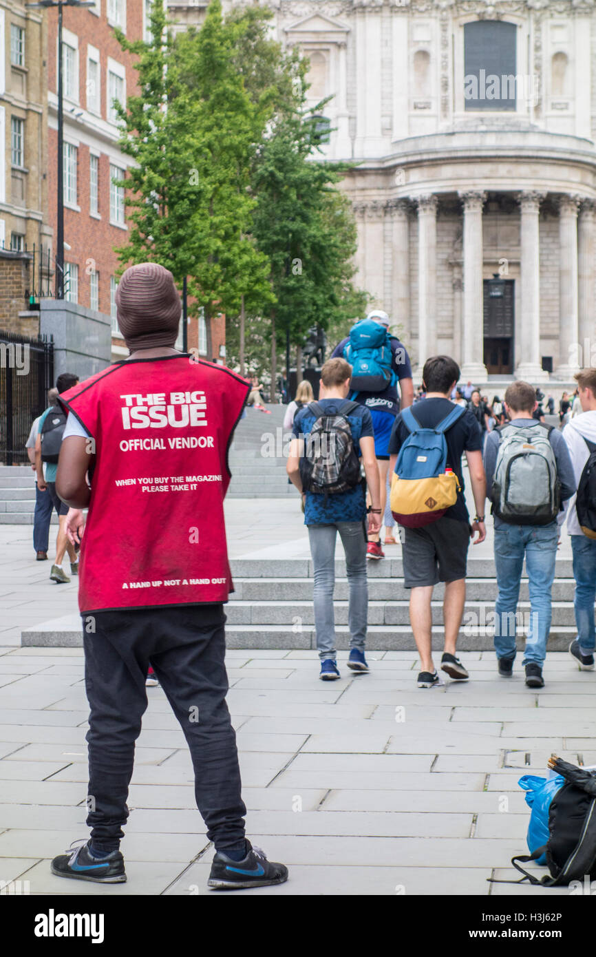 Der Big Issue Magazin offizielle Verkäufer in einen roten Wappenrock außerhalb St. Pauls Cathedral, City of London, UK Stockfoto