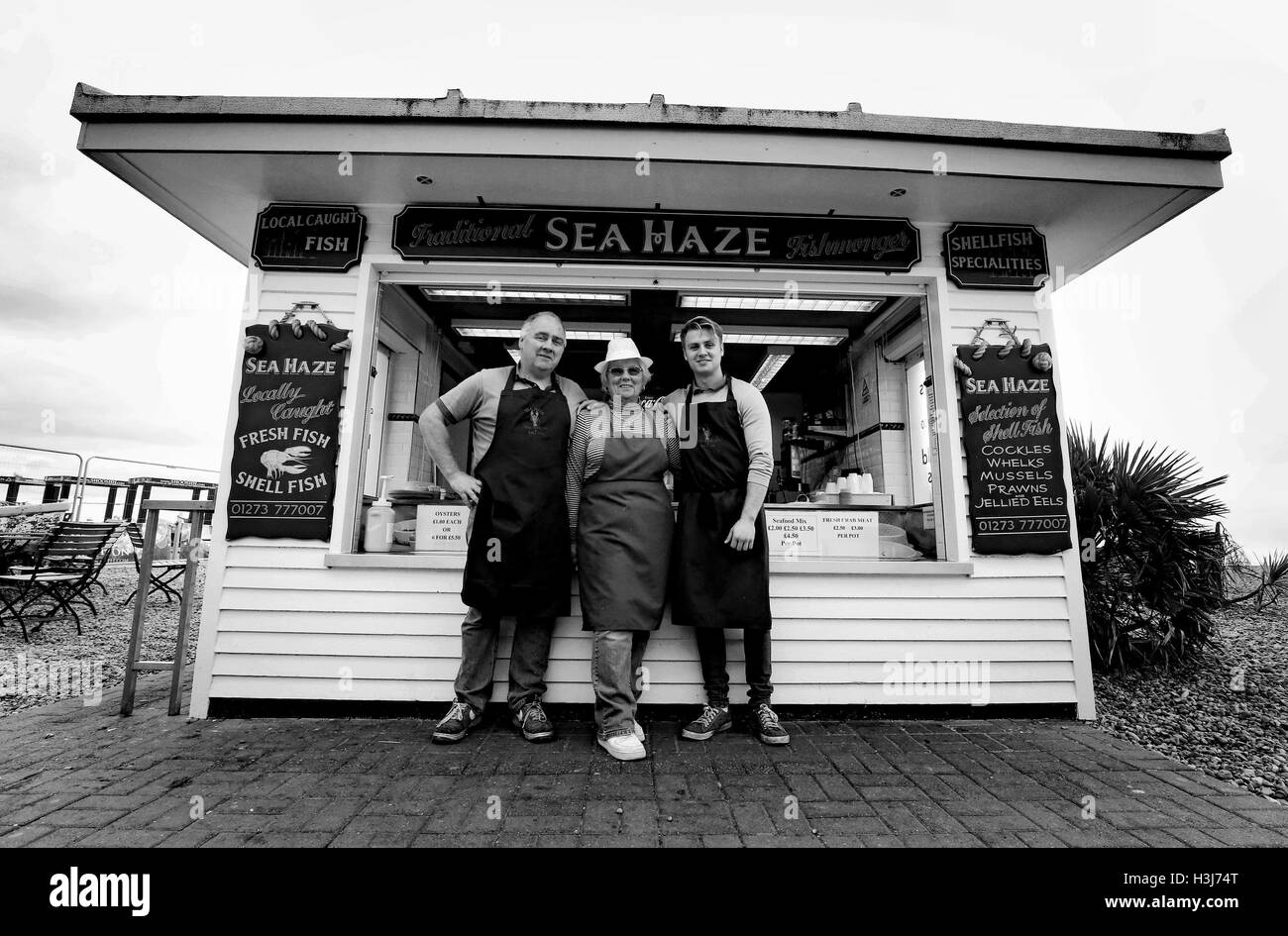 Anmerkung der Redaktion: Bild umgewandelt, BLACK AND WHITE Fischer Neil Messenger (links), Inhaber der Seahaze traditionelle Fischhändler in Brighton, East Sussex, steht vor seinem Kiosk am Strand von Brighton mit seiner Mutter Jackie und seinem Sohn Jack, die dazu beitragen, den Familienbetrieb als nationale Meeresfrüchte Woche bis zum 14. Oktober weiter. Stockfoto