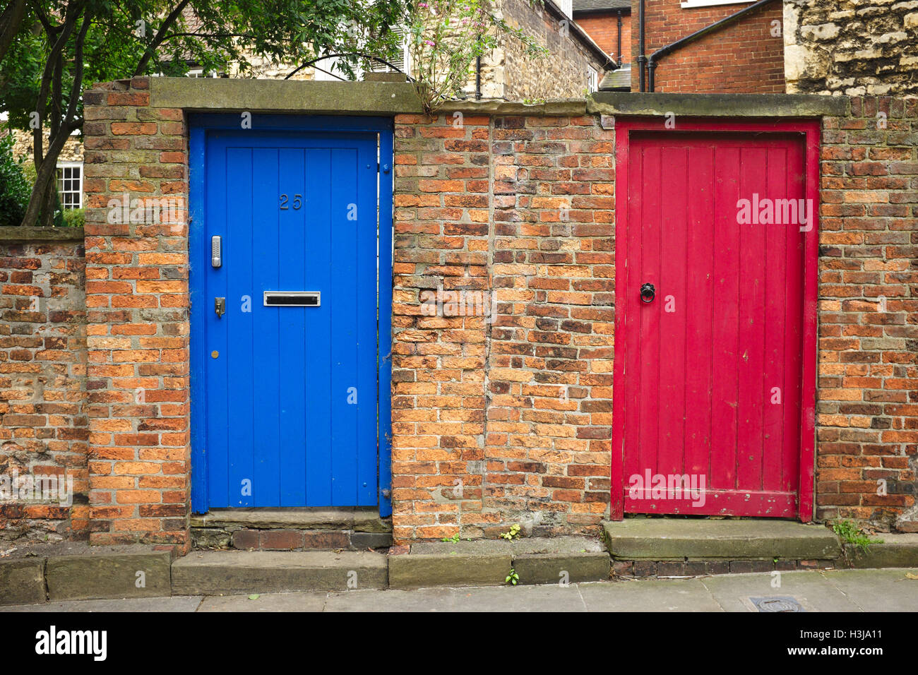 Eine rote Tür und eine blaue Tür in einer Mauer Stockfoto