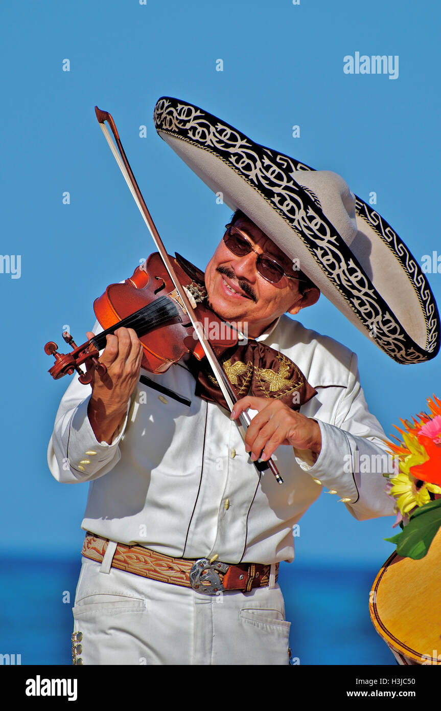 Mariachi Fiddler führt am Sunny Beach während der Hochzeit tragen einen Sombrero Hut & White Suite mit Gold Eimer in Mexiko Stockfoto