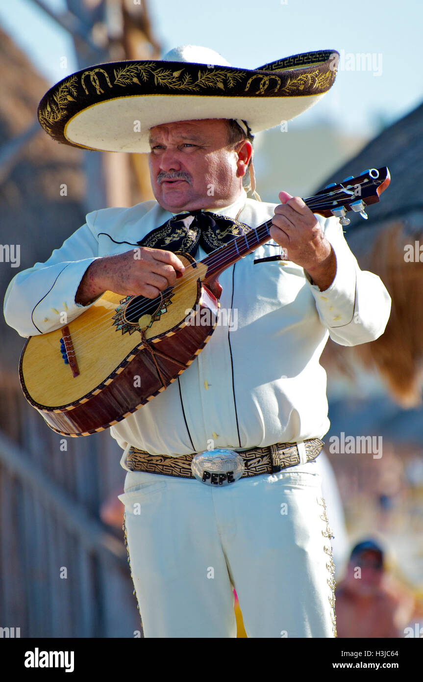 Mariachi Guitar Player führt am Sunny Beach während der Hochzeit tragen einen Sombrero Hut & White Suite mit Gold Eimer in Mexiko Stockfoto