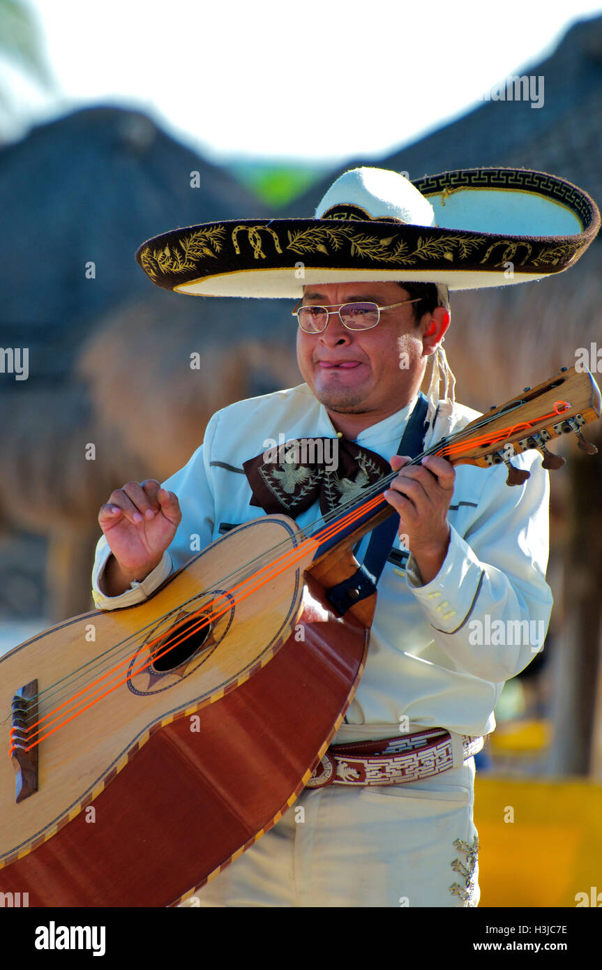 Mariachi Guitar Player führt am Sunny Beach während Hochzeit Sombrero Hut & weißen Anzug mit Gold Eimer in Mexiko Stockfoto