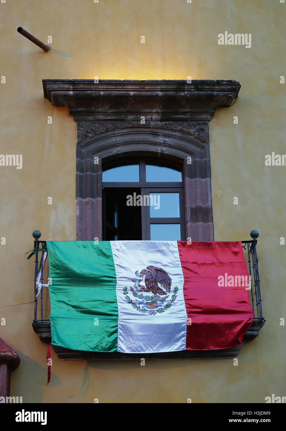 Mexikanische Flagge hängt von einem Balkon auf dem Marktplatz von San Miguel de Allende, Guanajuato, Mexiko. Stockfoto