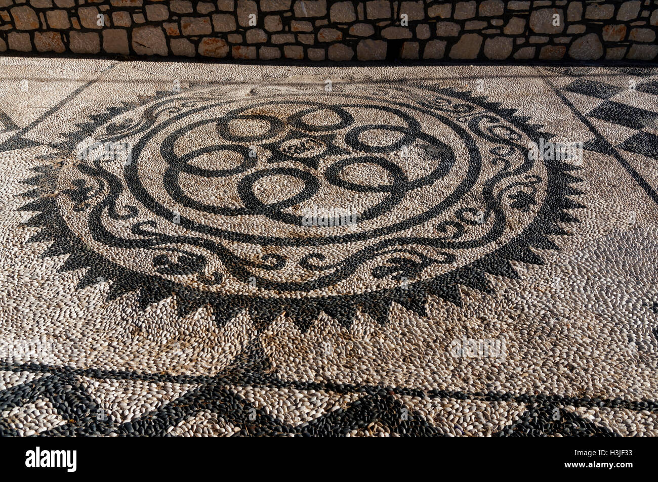 Design aus verschiedenen farbigen Kieselsteinen, Agios Nikolaos Kirche, Dorf von Emborio, Chalki Insel in der Nähe von Rhodos, Griechenland. Stockfoto