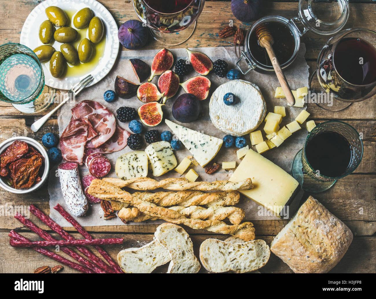 Wein und snack-Set mit verschiedenen Weinen in Gläser, Fleisch-Vielfalt, Ciabatta, sonnengetrocknete Tomaten, Honig, grüne Oliven, Feigen, Nüssen ein Stockfoto