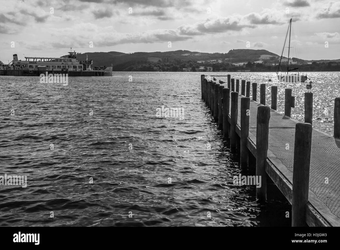 Eine monochrome Ansicht des Lake Windermere in Ambleside in der Lake District National Park, Cumbria mit Boot und Steg Stockfoto