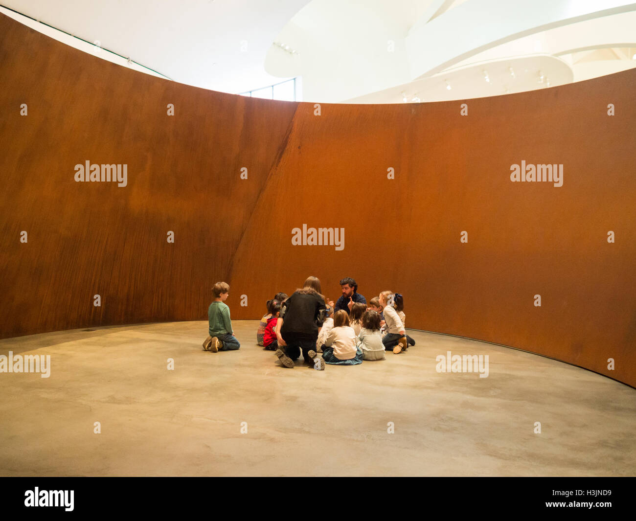 Schülerinnen und Schüler mit Lehrer sprechen über Kunst im Inneren Richard Serra Stahl-Skulptur im Guggenheim Museum Bilbao Stockfoto