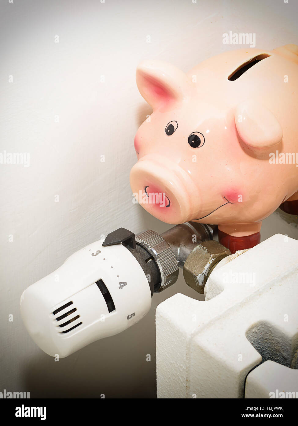 Sparschwein und das Ventil am Heizkörper zur Senkung der Energiekosten Stockfoto
