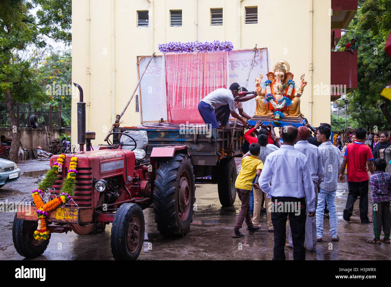 Junge Menschen, die beim Laden eine Ganesh-Statue auf einem Anhänger, Ganesh Chaturthi, Pune, Indien Stockfoto