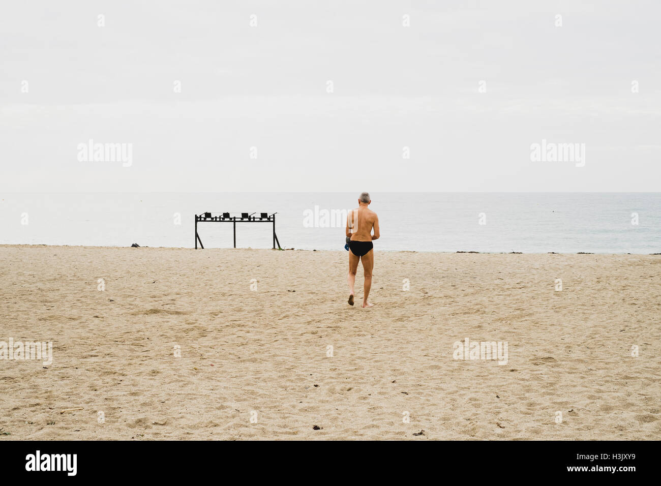 Ein älterer Mann Falmouths Gyllyngvase Strand entlang spazieren, schwimmen zu gehen Stockfoto