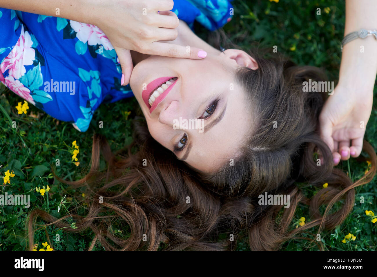 schöne junge Frau im blauen Kleid auf dem Rasen liegen entspannt Stockfoto
