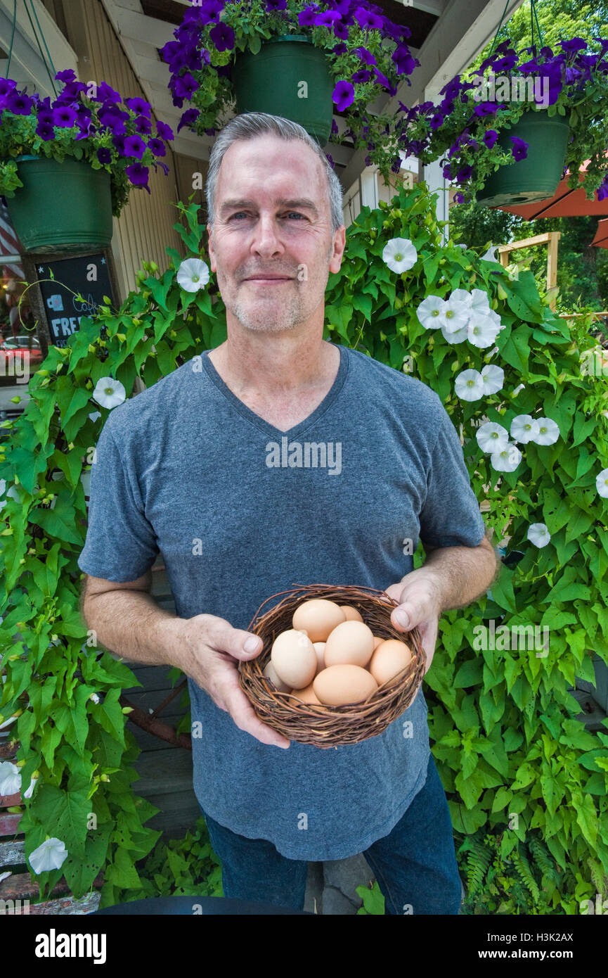 Café-Besitzer mit Korb mit frischen Eiern vor dem restaurant Stockfoto