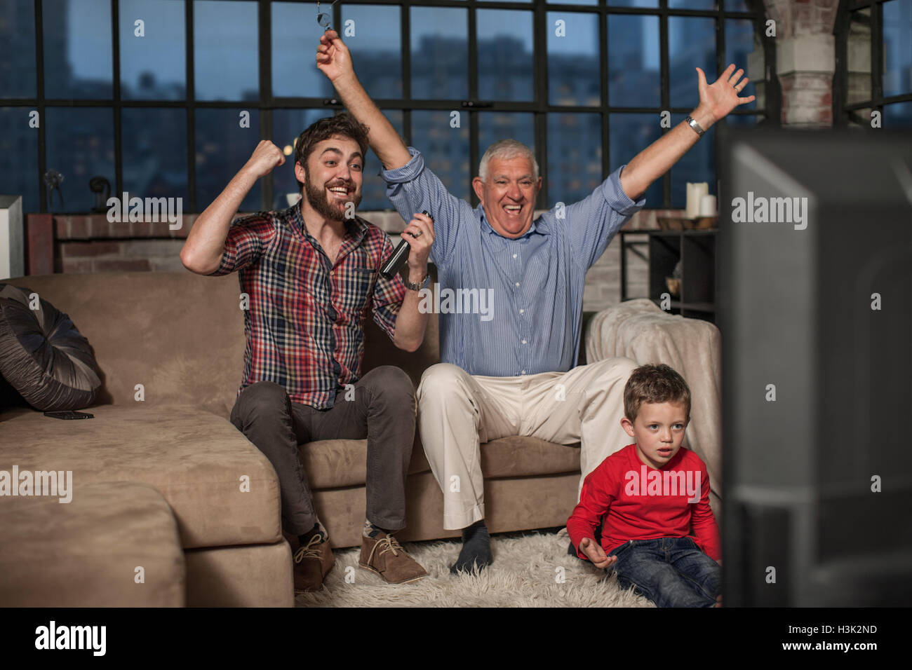 Drei-Generationen-Familie vor dem Fernseher zu Hause Stockfoto