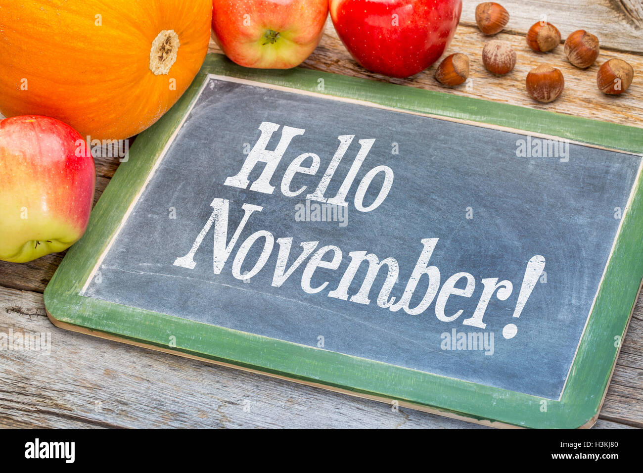 Hallo November auf einer Schiefertafel Tafel mit Kürbis, Äpfel und Haselnüsse gegen Grunge Scheune Holz Stockfoto