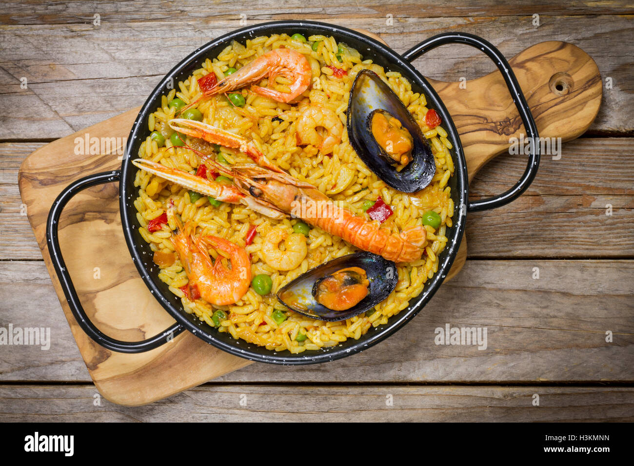 Spanische Paella auf einer hölzernen Matte auf einem Holztisch Stockfoto