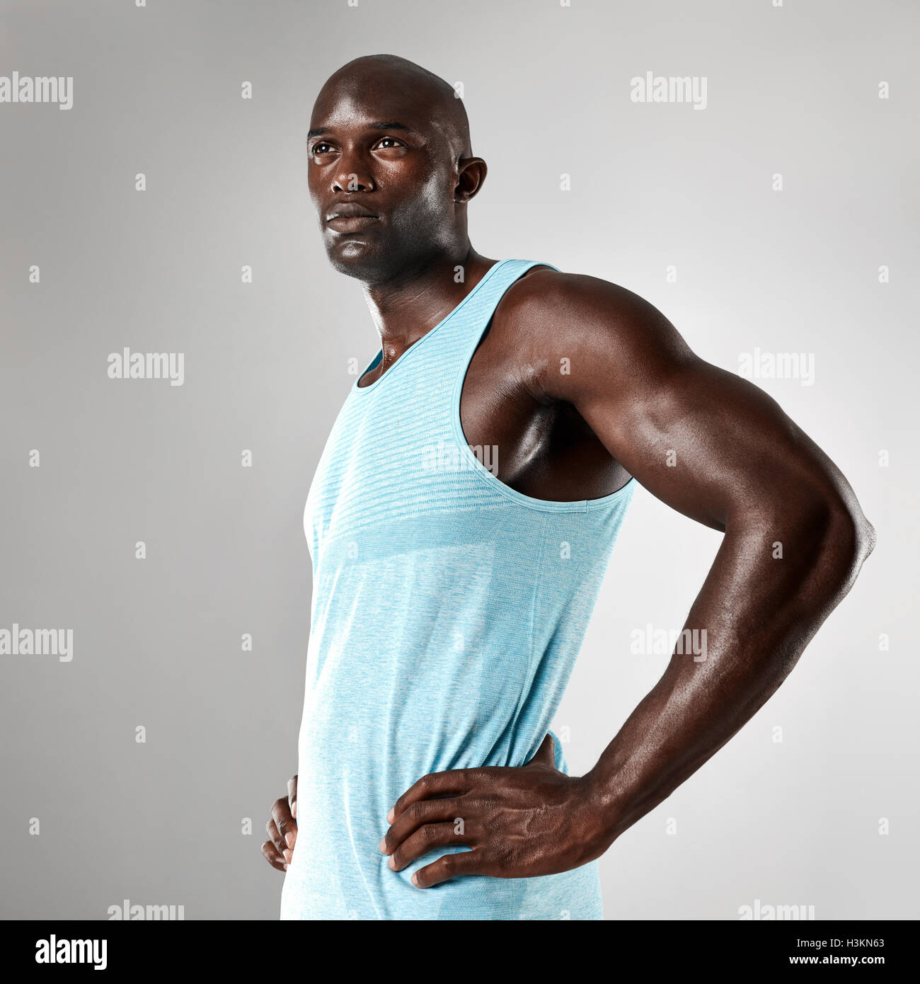 Porträt von gesunden jungen schwarzen Mann mit muskulösen Körper stehend vor grauem Hintergrund. Afro american Fitness-Modell mit Händen Stockfoto