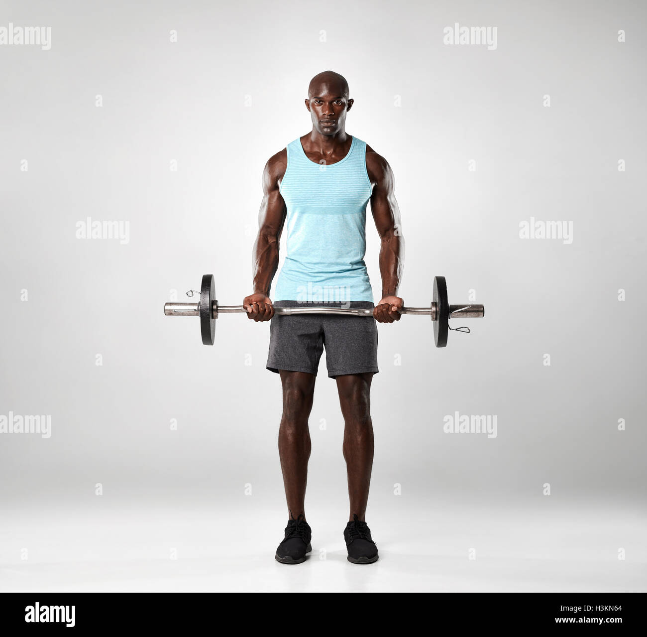 Voller Länge Schuss der afrikanischen männlichen Ausübung mit Langhantel. Muskulösen jungen Mann Training mit Gewichten auf grauem Hintergrund. Stockfoto