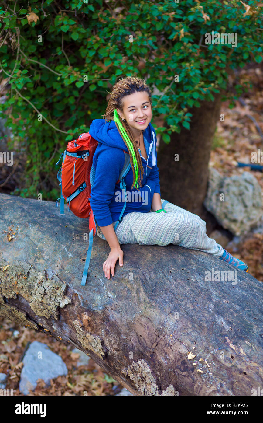 Niedliche Mädchen sitzen auf gefallenen Baum Stengel im wilden Wald Stockfoto