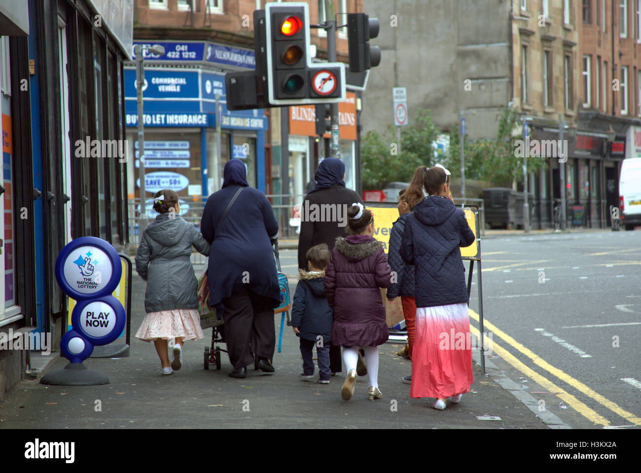 Asiatische Familie Flüchtling gekleidet Hijab Schal auf Straße in den UK alltägliche Szene Lotterie Zeichen Stockfoto