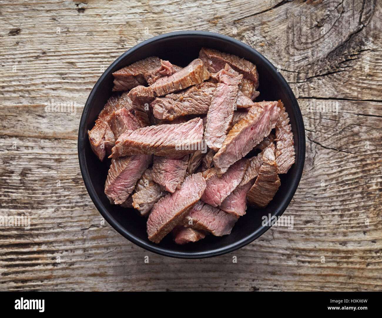 Schüssel mit gegrilltem Rindfleisch-Scheiben auf Holztisch, Ansicht von oben Stockfoto