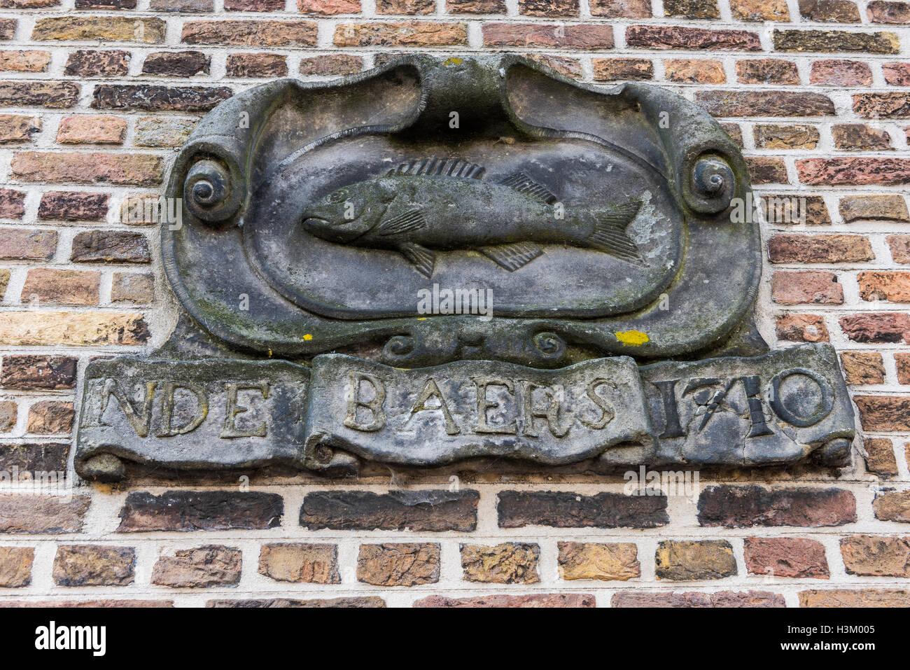 Statue in einer Wand eines alten Hauses mit Inschrift: 'Inde Baers"in der Stadt Dordrecht, Niederlande. Stockfoto